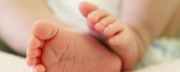 tiny-delicate-feet-of-newborn-baby-on-a-white-bed