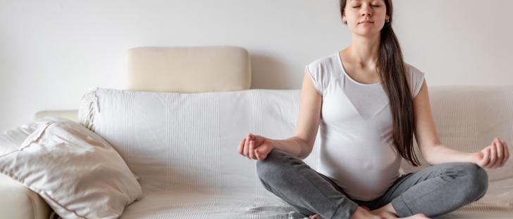 young-pregnant-woman-sitting-on-white-sofa-and-doing-yoga