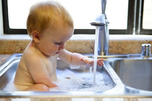 Baby bathing in kitchen sink