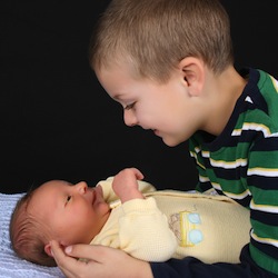 Brother smiling at newborn sibling
